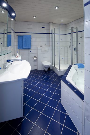 Modernes Badezimmer mit blauen Fliesen, Dusche, Waschbecken und Toilette.