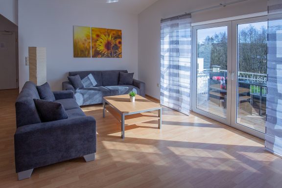Moderne Wohnzimmereinrichtung mit Sofa, Tisch und Fenster, Blick nach draußen.