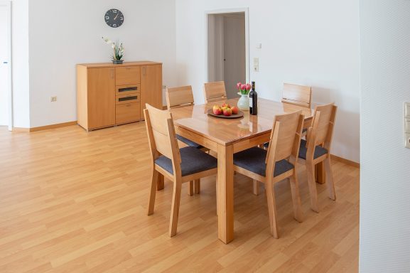 Heller Essbereich mit Holztisch, sechs Stühlen und Obstschale.